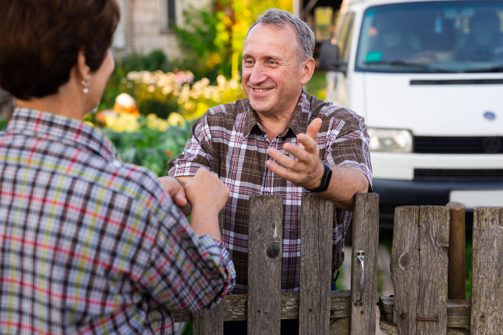 Neighbors,Middle,Aged,Man,And,Woman,Chatting,Near,The,Fence